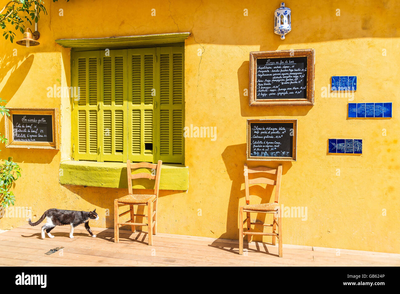 CALVI, Korsika - 28. Juni 2015: Katze und Stühlen vor traditionelles Restaurant im Hafen von Calvi. Korsika hat viele c Stockfoto