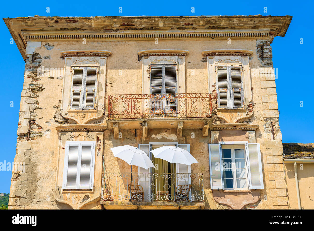 Zwei weiße Sonnenschirme auf Balkon eines typischen alten Haus in Erbalunga Stadt, Korsika, Frankreich Stockfoto