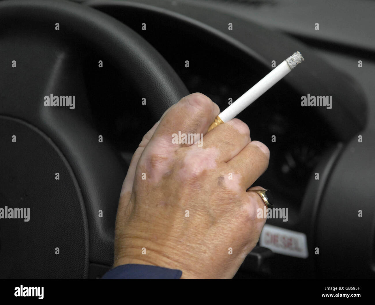 Lobbyisten fordern ein Rauchverbot in Autos. Ein Mann hält eine Zigarette, während er in London am Steuer eines Autos sitzt. Stockfoto