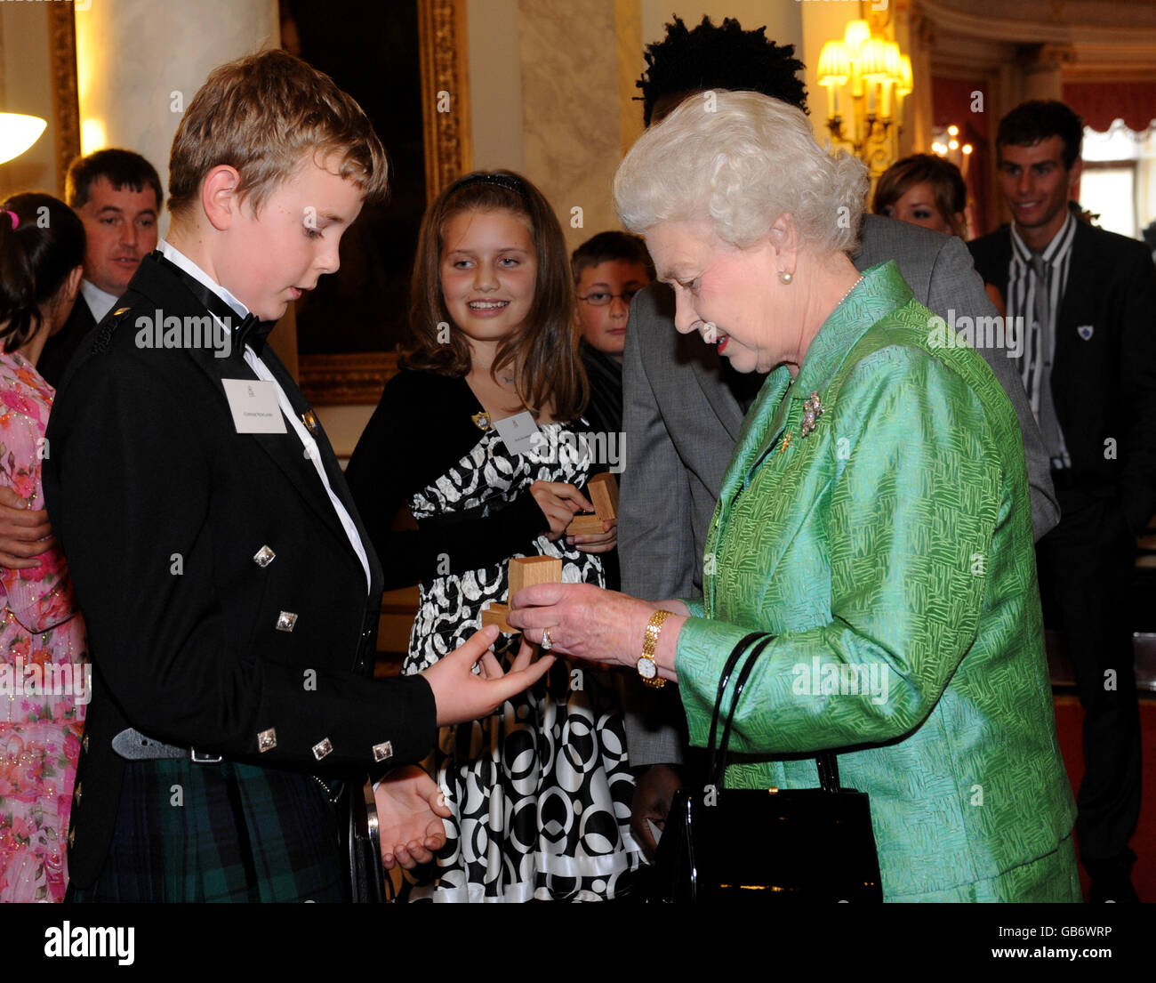 Die britische Königin Elizabeth II. Überreicht Connor Newlands (12) aus Schottland, der seine Schwester Gemma vor dem Ertrinken rettete, während eines Empfangs anlässlich des 50. Jahrestages der BBC-Kinderfernsehsendung im Buckingham Palace, London, ein goldenes Blue-Peter-Abzeichen. Stockfoto