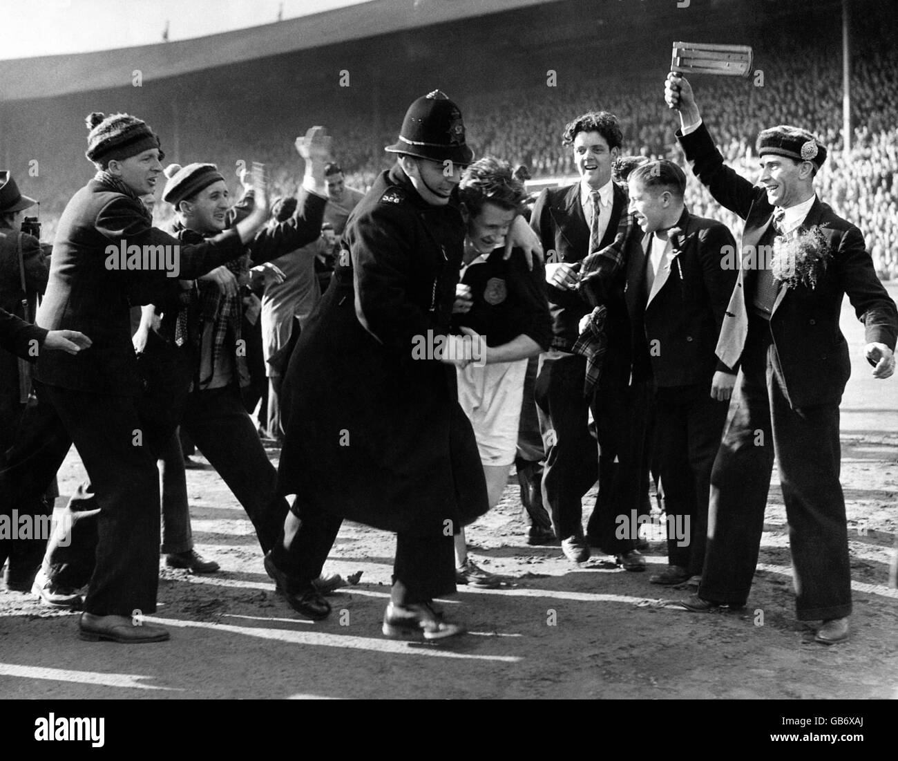 Der schottische Kapitän George Young wird von einem Polizisten vom Spielfeld gehetzt, um den begeisterten Glückwünschen der schottischen Fans nach dem Sieg ihres Teams mit 3:1 zu entgehen. Stockfoto