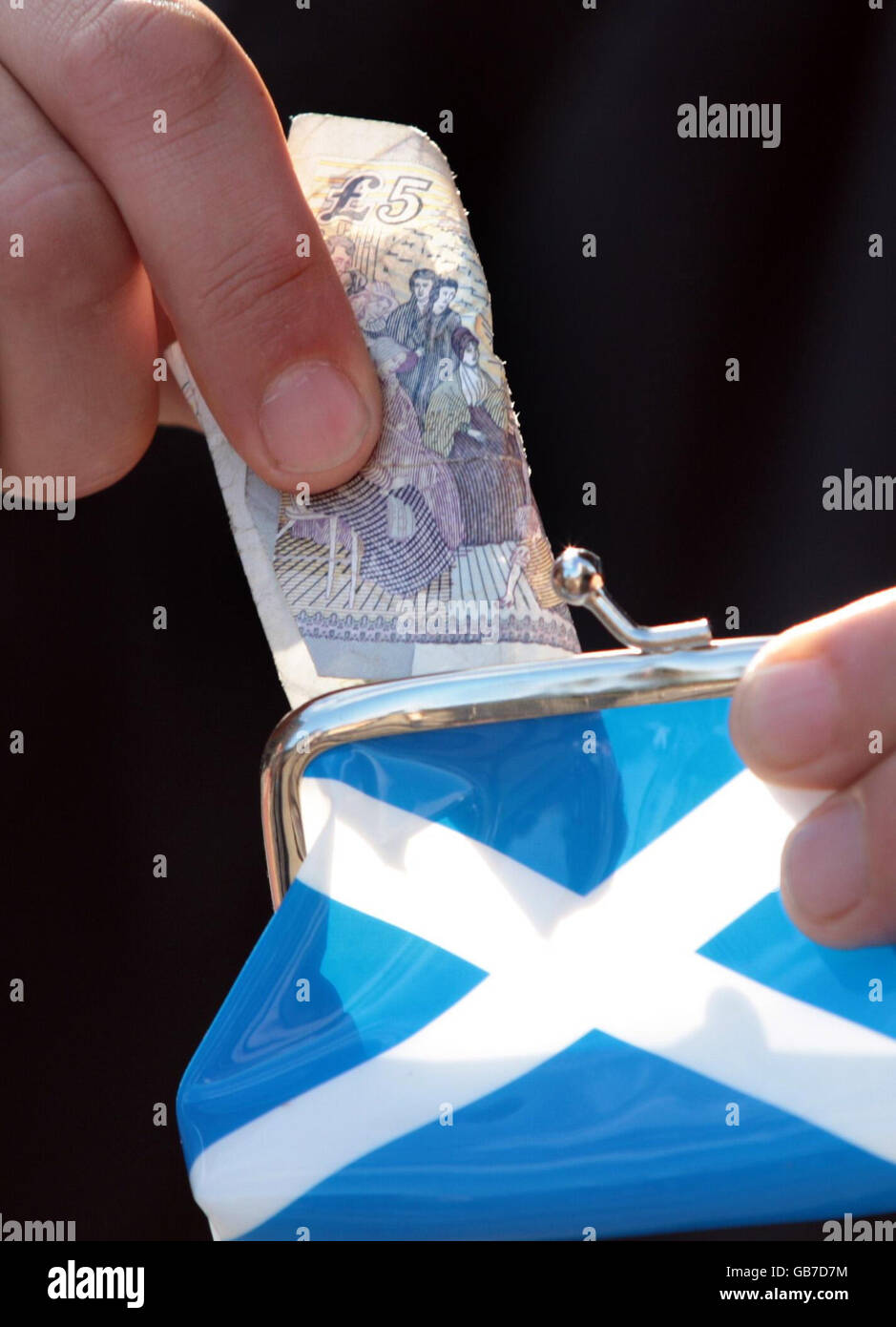 Eine 5-Pfund-Note wird in eine Geldbörse mit einem Saltyre (der Flagge Schottlands) auf der Seite gelegt. Prognostiker deuten darauf hin, dass sich die Wirtschaft bereits in einer Rezession befindet. Stockfoto