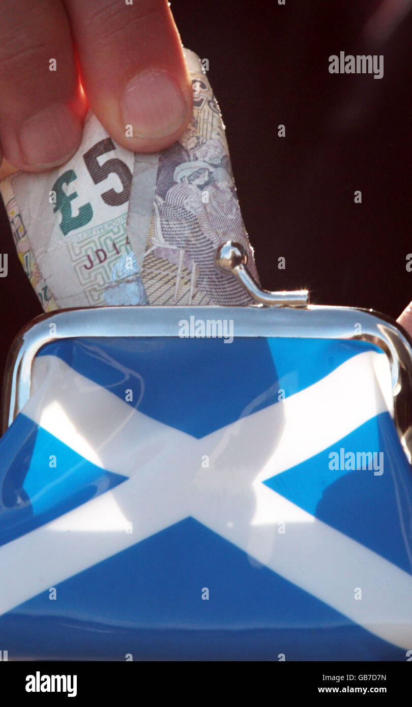 Eine 5-Pfund-Note wird in eine Geldbörse mit einem Saltyre (der Flagge Schottlands) auf der Seite gelegt. Prognostiker deuten darauf hin, dass sich die Wirtschaft bereits in einer Rezession befindet. Stockfoto