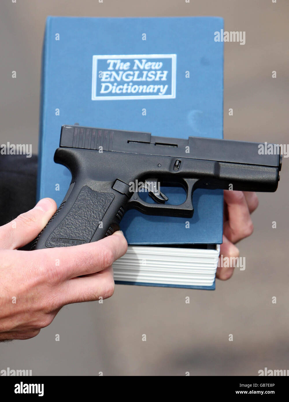 Ein CPS-Offizier hält eine Pistole, die in einem als Buch verkleideten Fall gehalten wurde, das dem gefälschten MI5-Agenten Marcus Alder von Offord D'Arcy, Cambridgeshire, gehört. Stockfoto