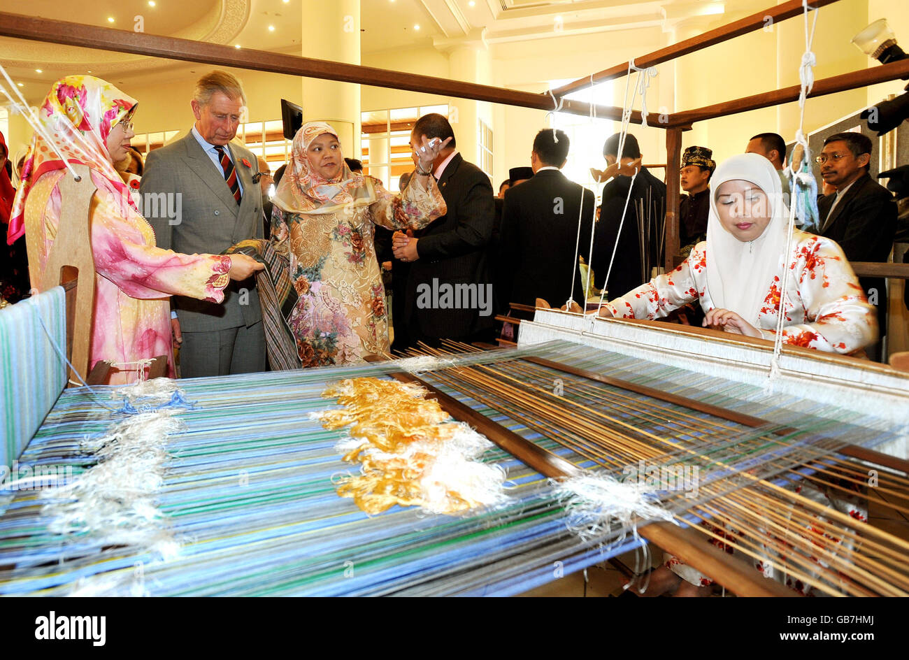 Der Prinz von Wales sieht zu, wie traditionelle Brunei-Seide gewebt wird, während er auf einer Kunsthandwerksmesse an der Universität von Brunei unterwegs ist. Stockfoto