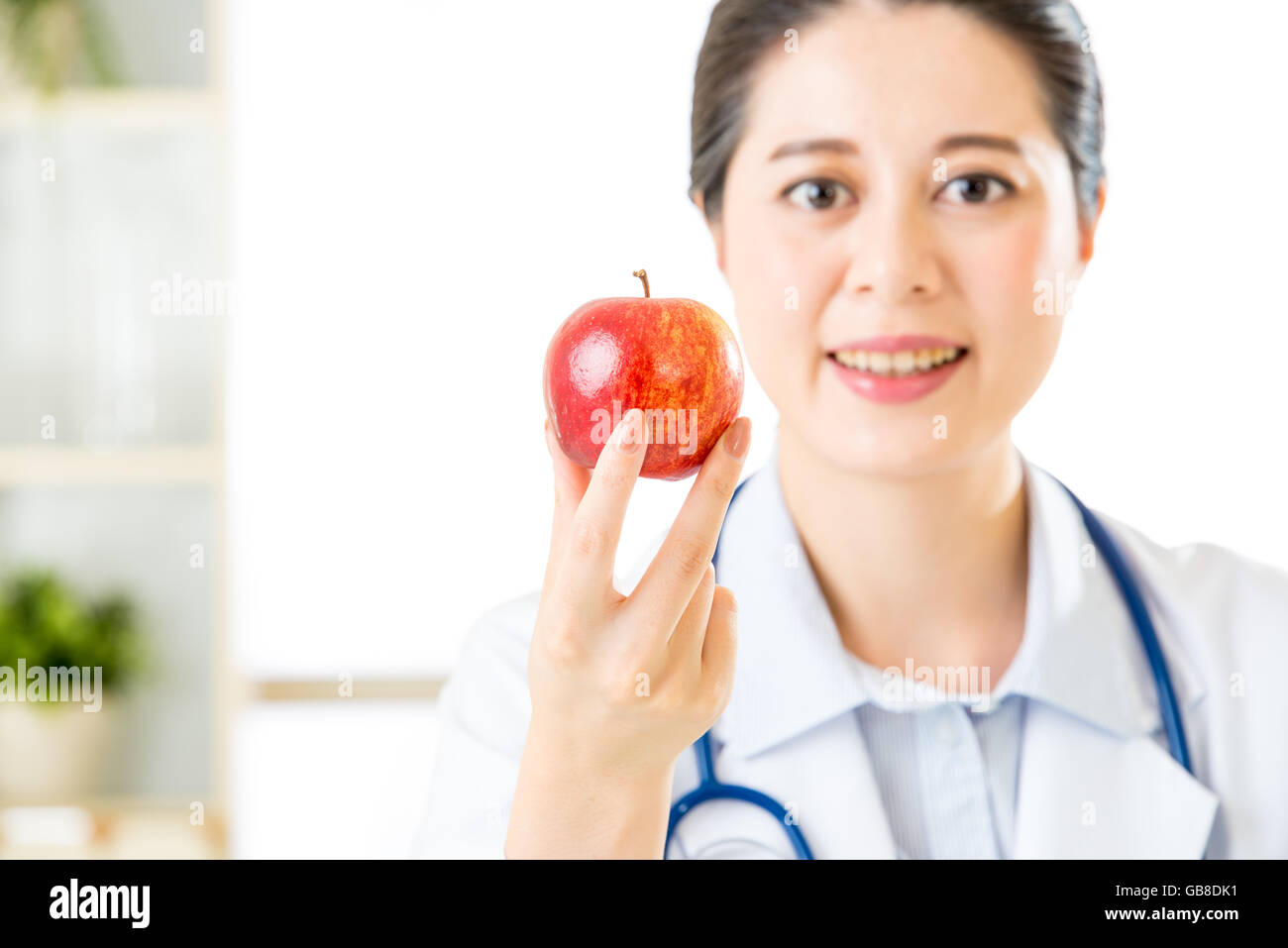 Junge asiatische Ernährungsberaterin hält einen Apfel, gesundes Essen Stockfoto