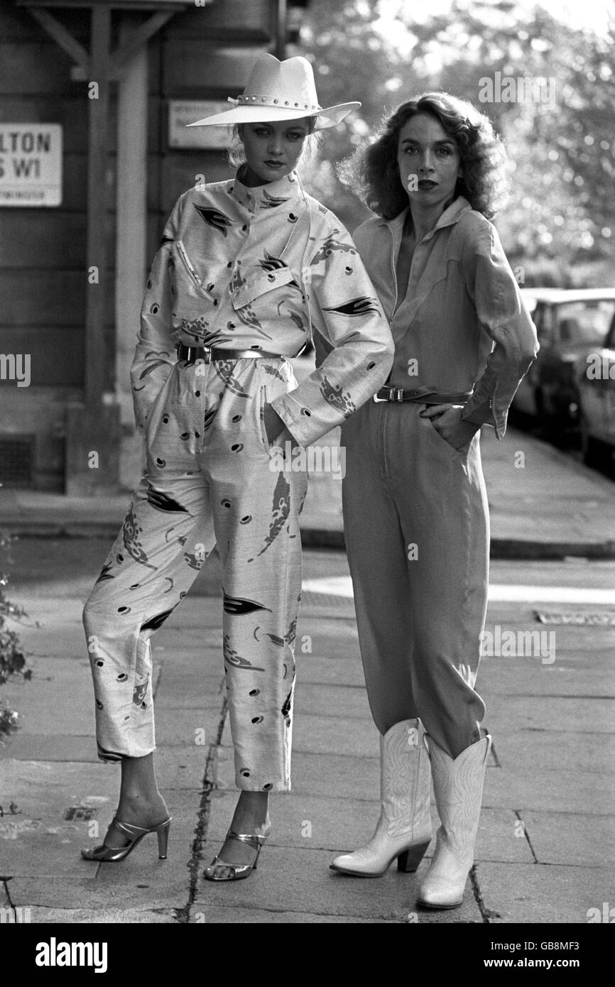 Cheryl Matthews (links) in Brian Baker's rohem Seidenjumpsuit für den späten Tag und Felicity in Charlotte Flood's Seidenflieger-Anzug in Türkis und Gelb. Stockfoto