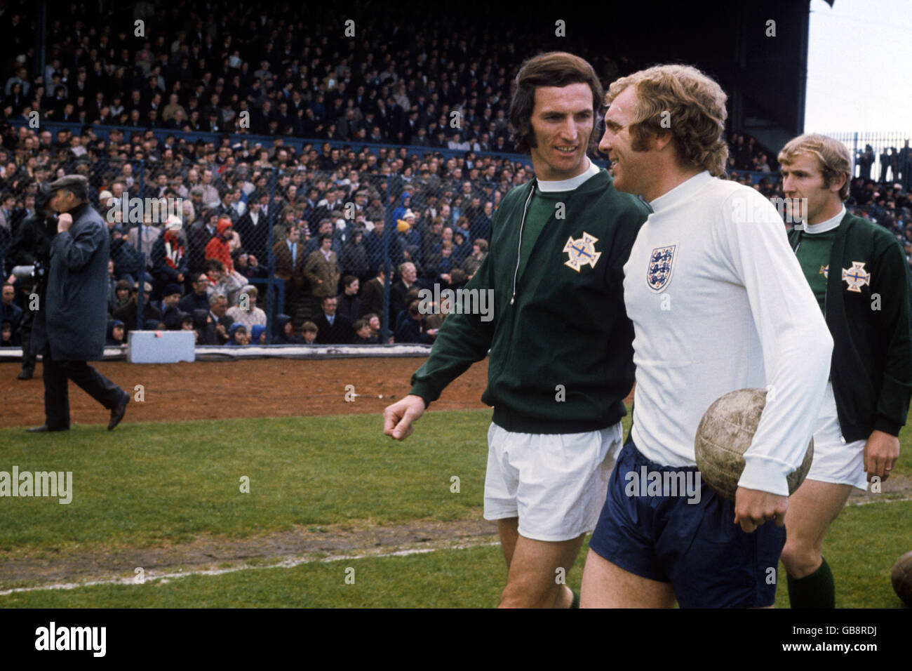 Englands Kapitän Bobby Moore (c) geht vor dem Anpfiff mit dem nordirischen Kapitän Derek Dougan (l) auf das Spielfeld. Ebenfalls abgebildet ist der nordirische Dave Clements (r). Stockfoto
