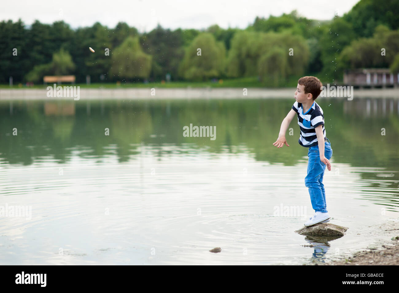 aktiver junge wirft Steinchen in den See Stockfoto