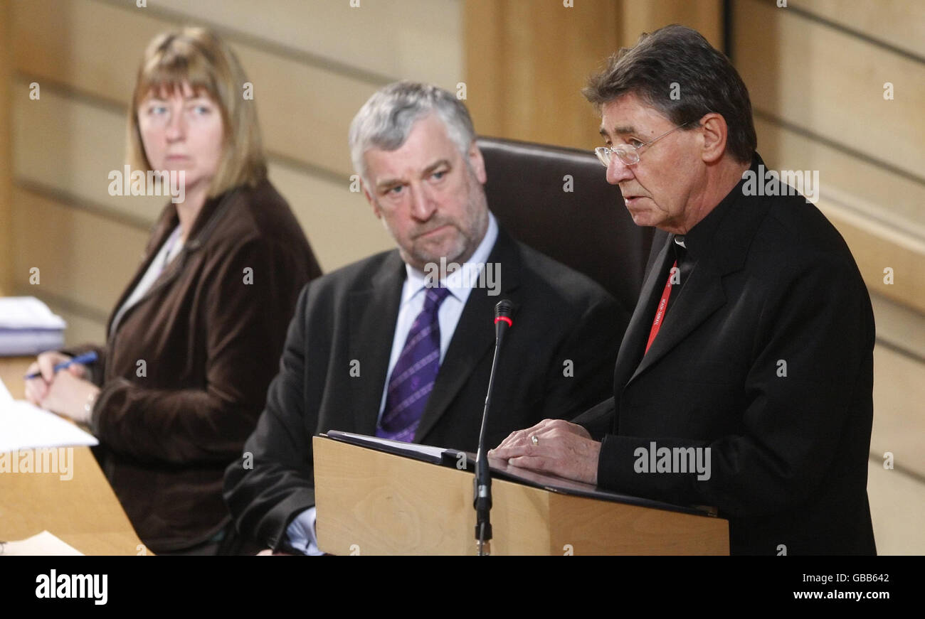 Der sehr Rev Patrick Keegans, der zum Zeitpunkt der Lockerbie-Katastrophe Pfarrer von Lockerbie's Holy Trinity Roman Catholic Church war, spricht vor dem schottischen Parlament in Edinburgh, beobachtet von der schottischen Parlamentsabgeordneten Jennifer Smart (links) und dem Vorsitzenden Alex Fergusson (Mitte). Stockfoto