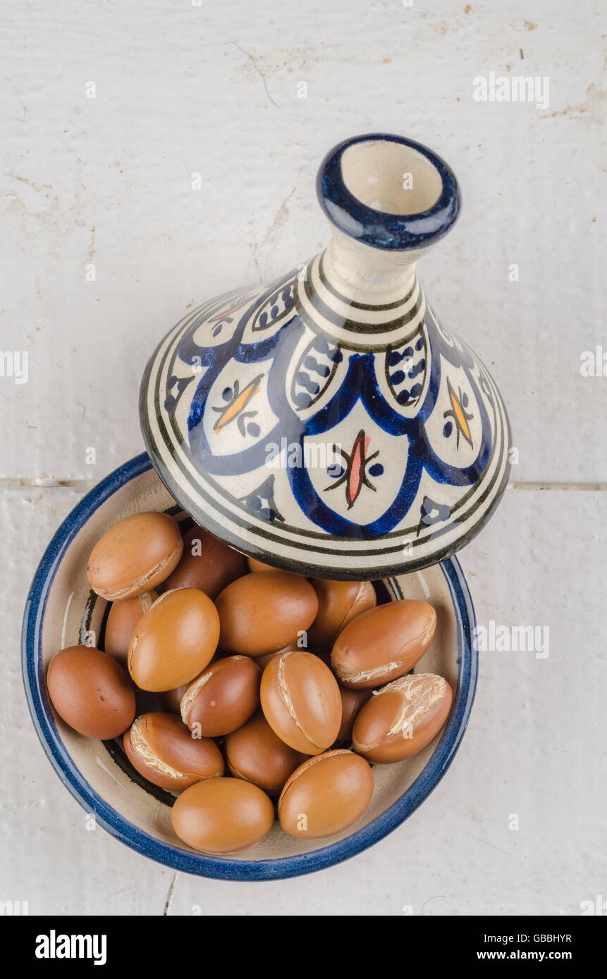 Argan-Früchte auf einer hölzernen Tischplatte in einer marokkanischen Tajine Stockfoto