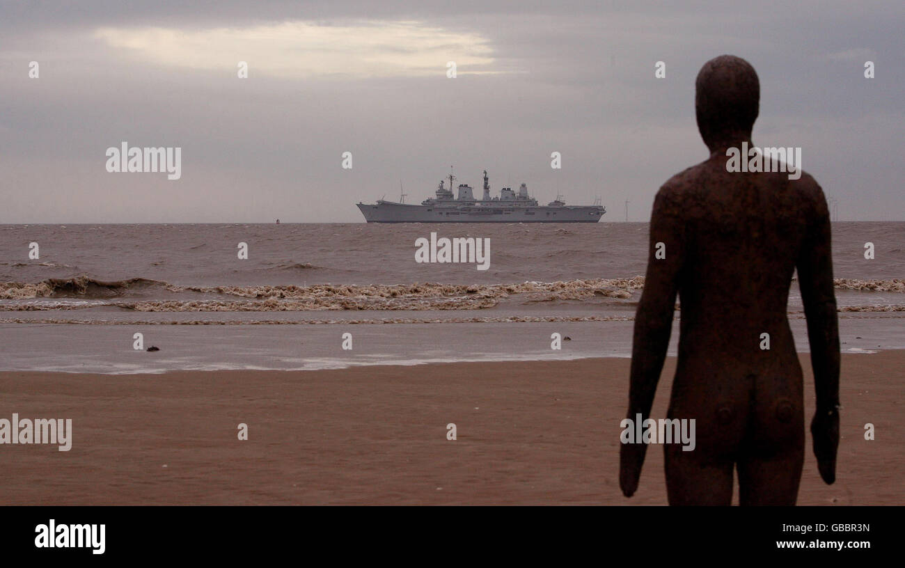 HMS Ark Royal geht an den Gormley Statuen in Crosby Beach, Merseyside vorbei, bevor sie in Liverpool anlegt. Stockfoto