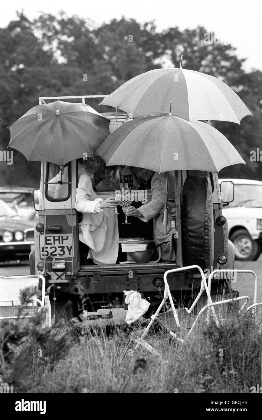 Zwei picknickende Rennfahrer auf der Rückseite eines Land Rover, entschlossen, die Hochstimmung auf dem Parkplatz des verregneten Royal Ascot weiterzuführen. Stockfoto