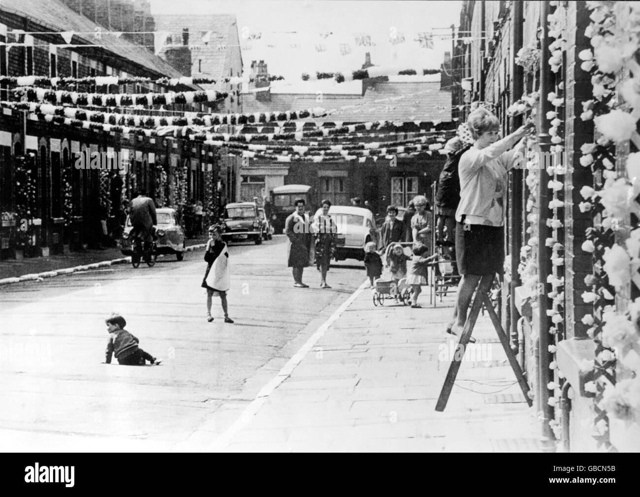 Eine Liverpooler Hausfrau in einer terrassenförmigen Straße in der Nähe des Goodison Parks Verleiht der WM-Straßendekoration den letzten Schliff Stockfoto