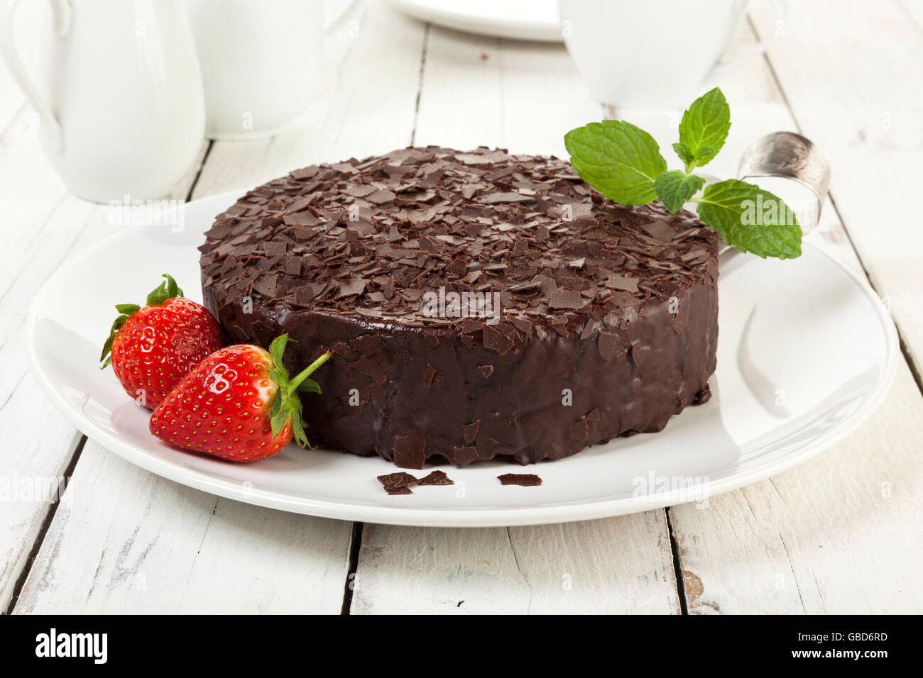 Schokoladenkuchen auf einen Teller garniert mit Erdbeeren auf rustikalen Couchtisch Stockfoto