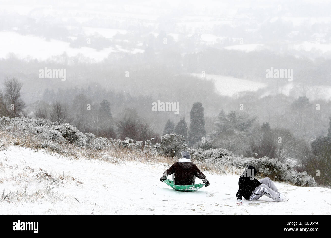 Zwei Jungen nutzen die Wetterbedingungen, um auf den Malvern Hills, Worcestershire, Schlittenfahren zu gehen. Stockfoto