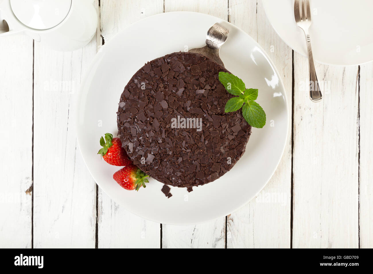 Schokoladenkuchen auf einen Teller garniert mit Erdbeeren auf rustikalen Tisch, Ansicht von oben Stockfoto