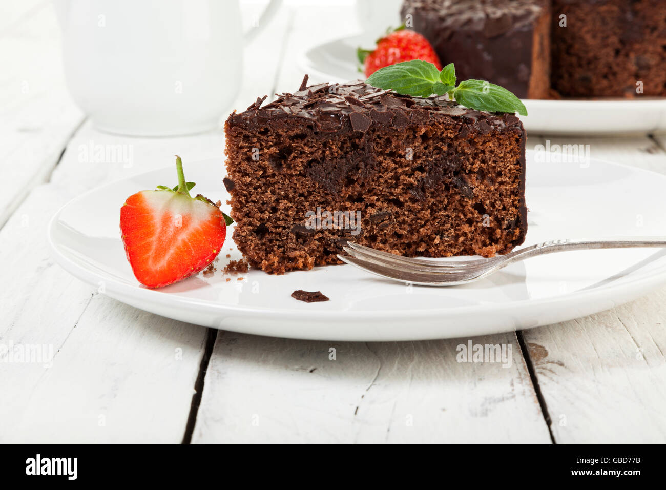 Stück Schokoladenkuchen auf einen Teller garniert mit Erdbeeren auf rustikalen Tisch Stockfoto