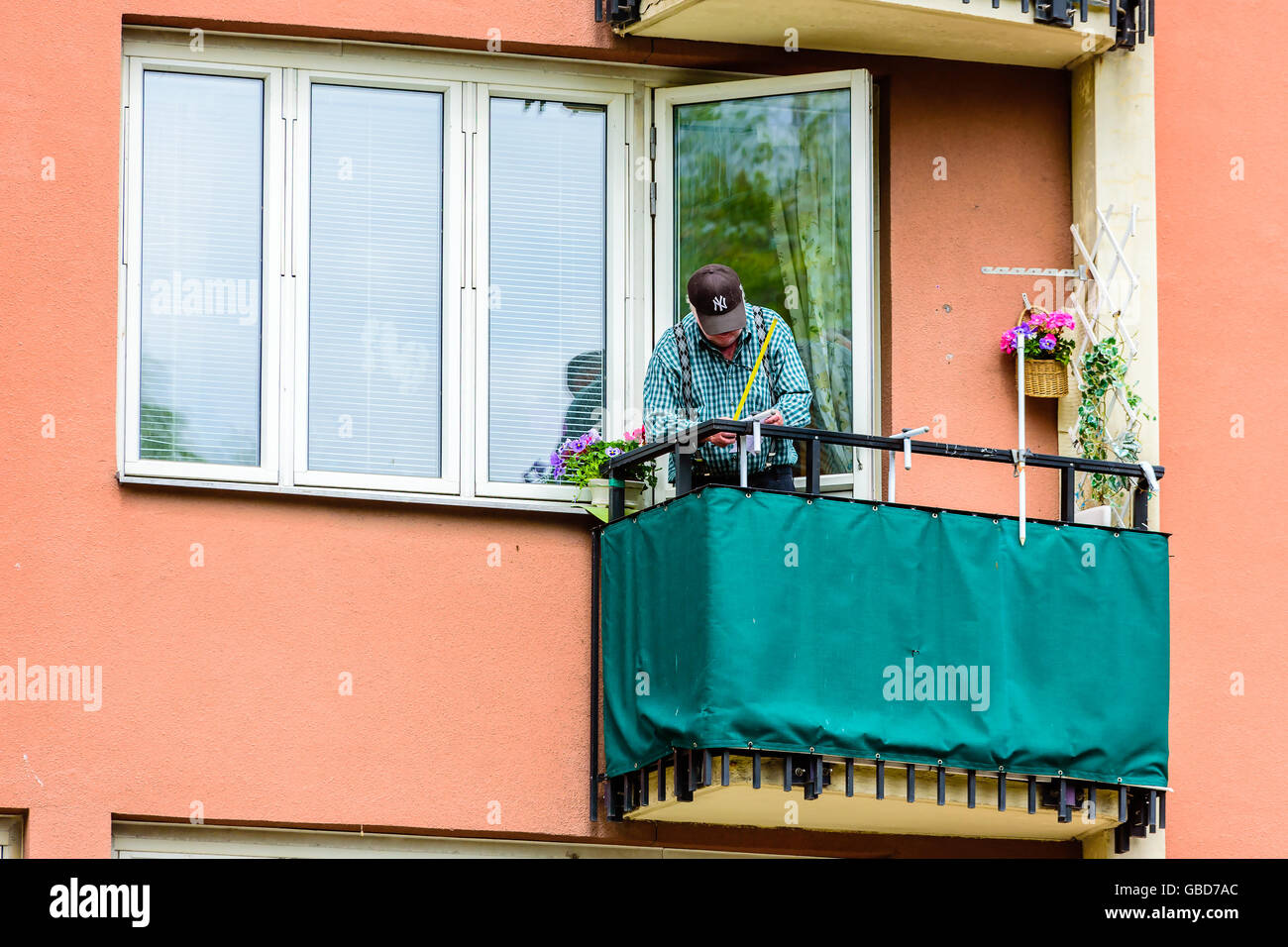 Motala, Schweden-21. Juni 2016: Senior woman Messen auf einen Balkon. Ha hat ein kleines Stück Papier in der Hand als auch. Stockfoto