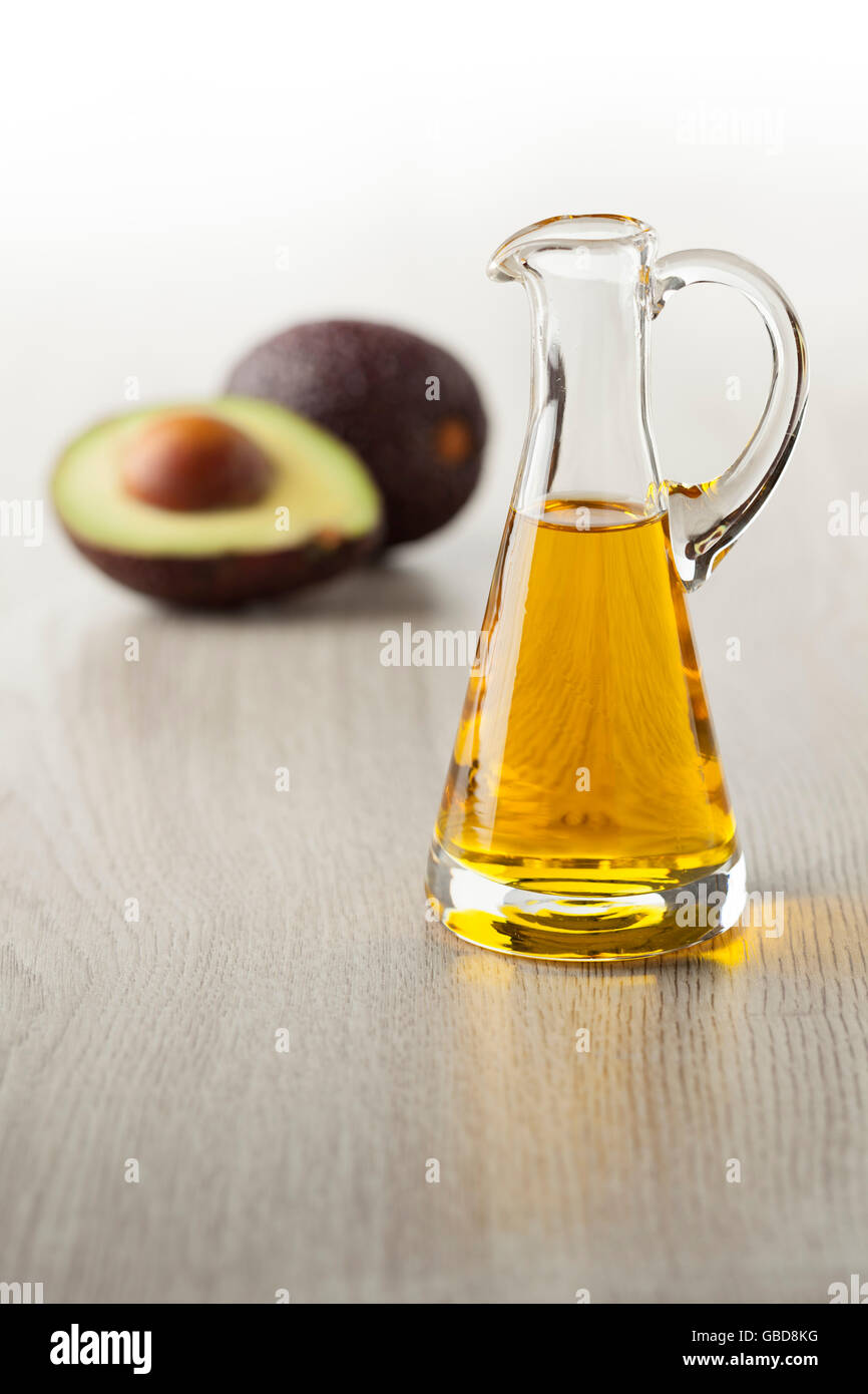 Flasche von Avocado-Öl und frische Avocado im Hintergrund Stockfoto