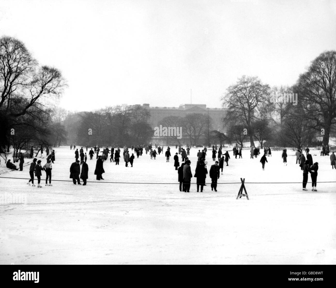 Im Schatten des Buckingham Palastes fahren Schlittschuhe und Slider auf das Eis des gefrorenen St. James' Park Lake. Stockfoto
