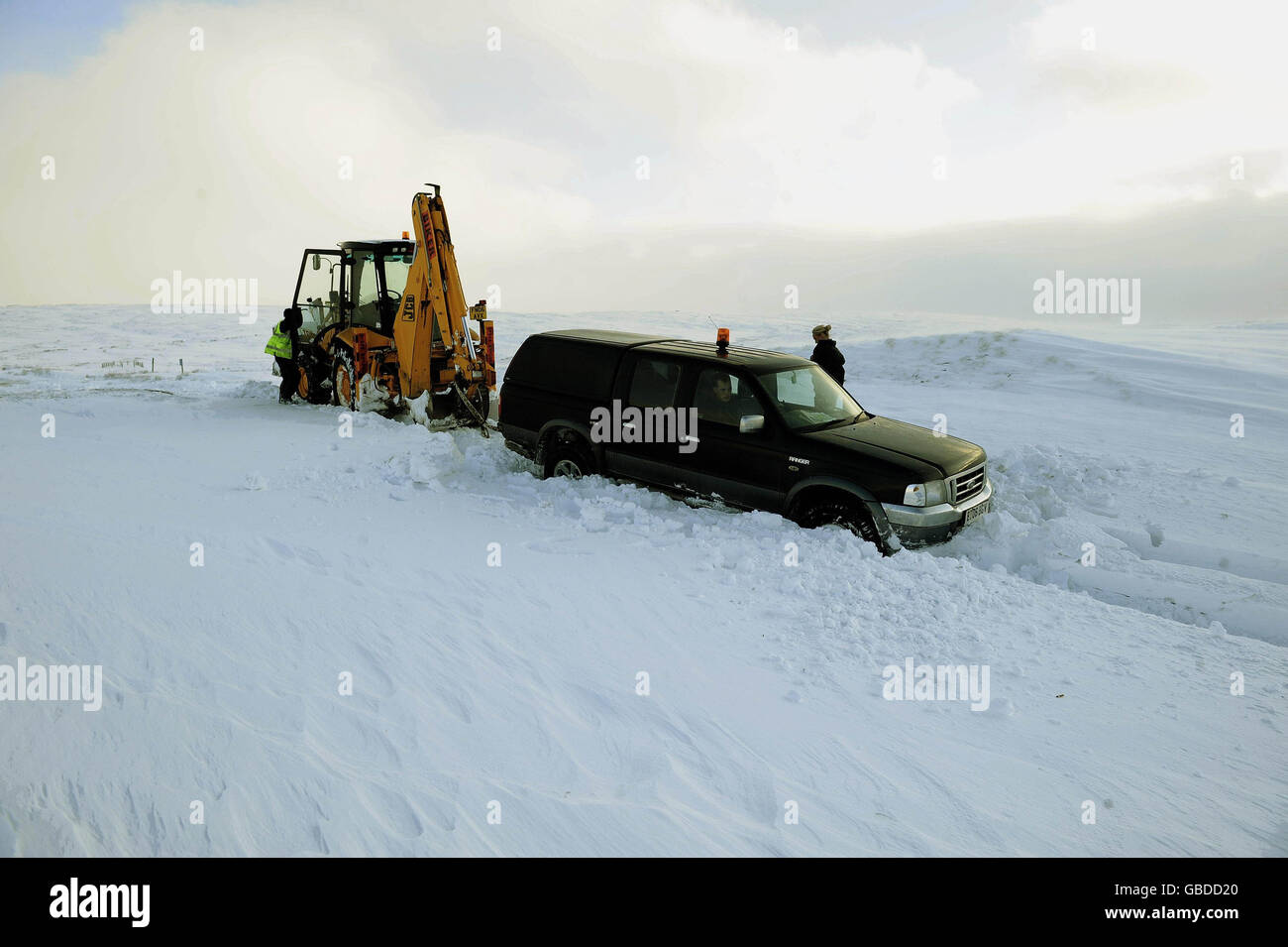 Ein JCB hilft, ein 4x4-Fahrzeug in der Nähe von Tan Hill in North Yorkshire zu erholen, als es im Schnee stecken blieb. Stockfoto