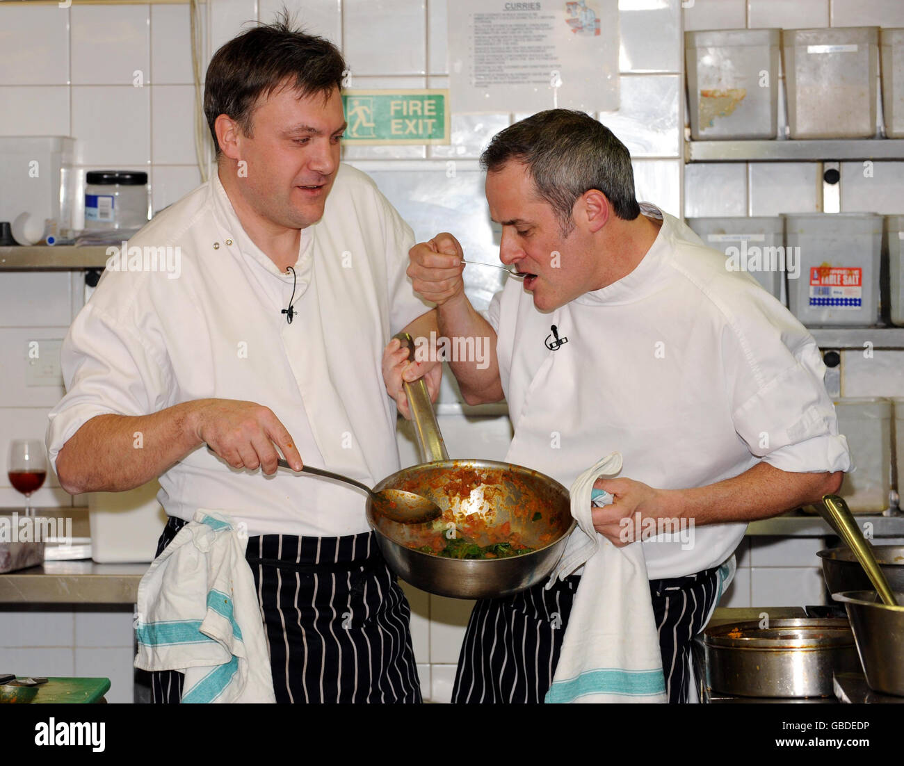 Der Schulsekretär Ed Balls (links) und der Fernsehkoch Phil Vickery bereiten in der Küche des Cinnamon Club Restaurants in Westminster, im Zentrum von London, aus einem Rezeptheft ein eigenes Gericht zu, das im Rahmen einer Regierungsangelegenheit, die Kinder zum Kochen anregt, an die Schüler des Landes verteilt werden soll. Stockfoto