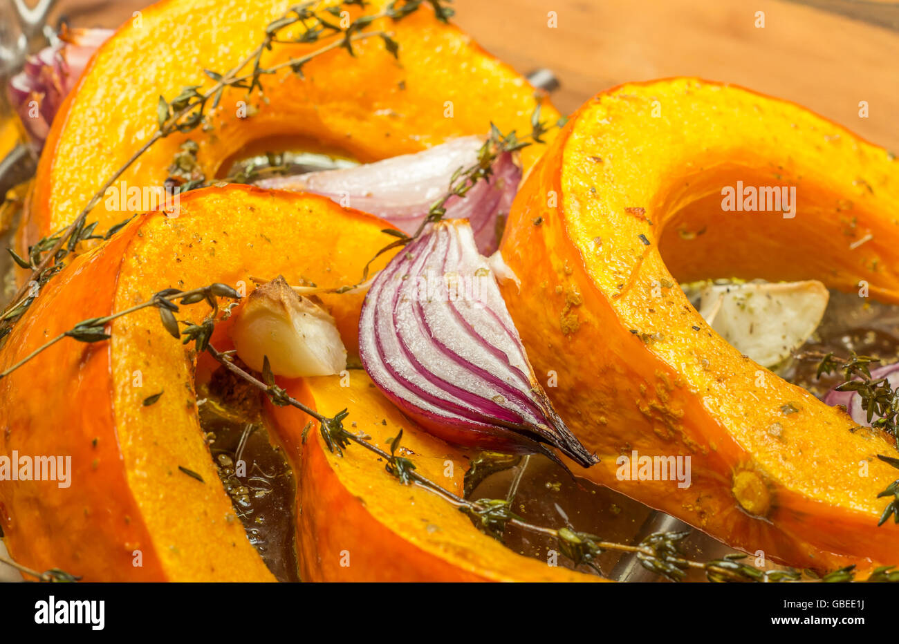 Gebratener Kürbis mit roten Zwiebeln, Knoblauch und Thymian in eine Auflaufform legen Stockfoto