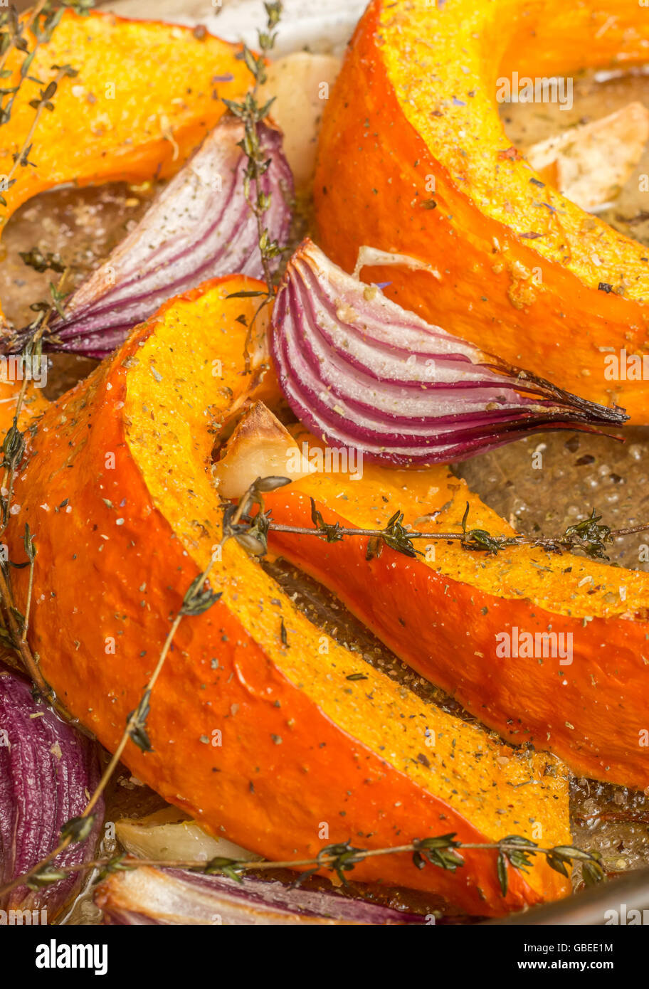 Gebratener Kürbis mit roten Zwiebeln, Knoblauch und Thymian in eine Auflaufform legen Stockfoto