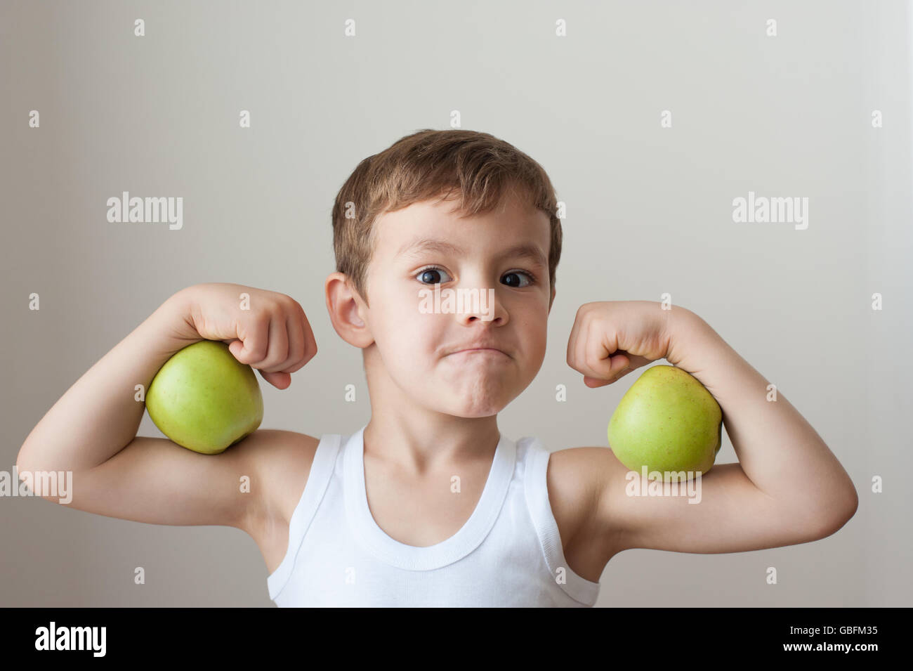 gesunde junge mit grünem Apfel zeigt Muskeln Stockfoto