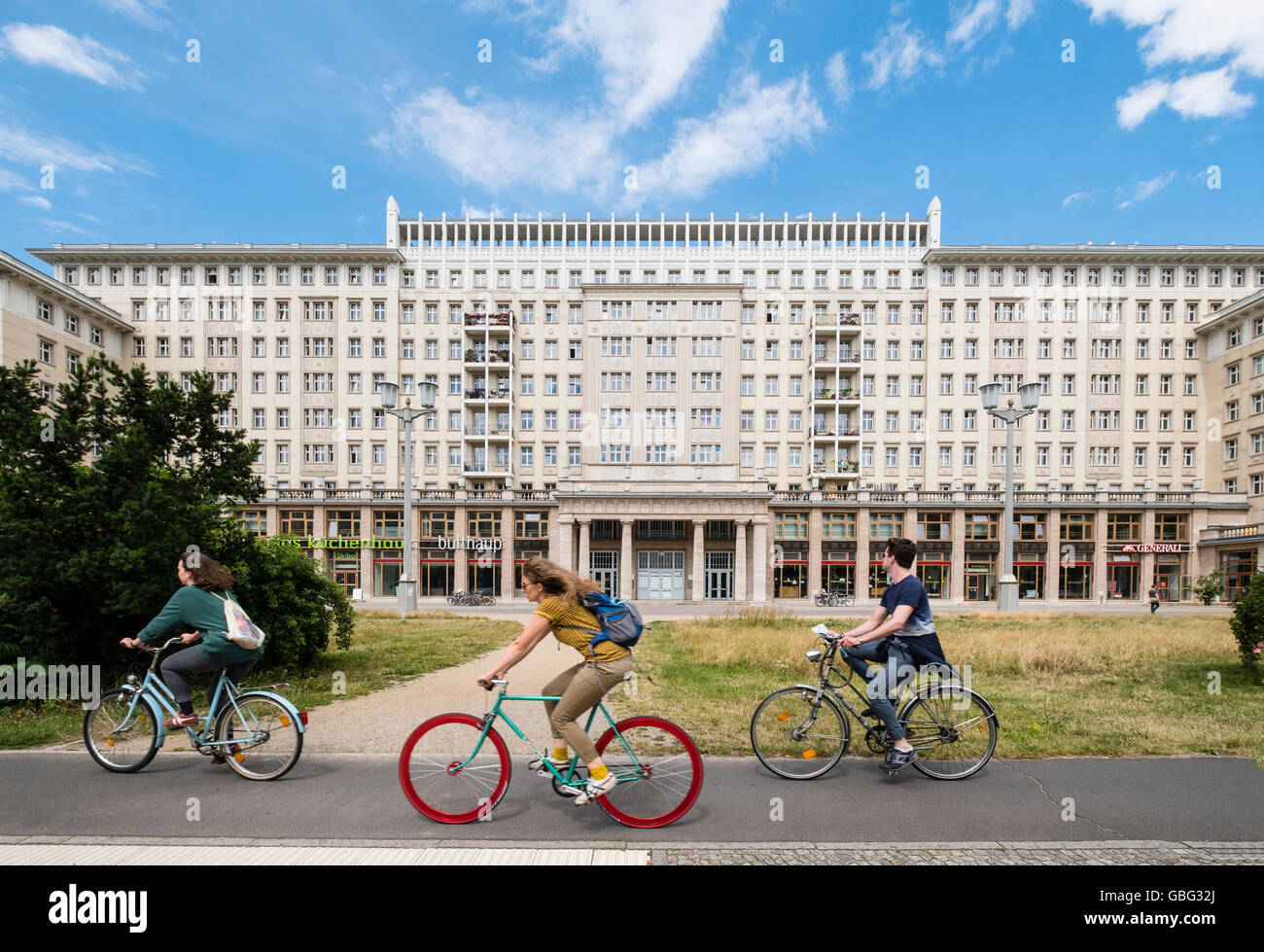 Radfahrer fahren vorbei an historischen sozialistischen ehemaligen DDR Mehrfamilienhäuser auf der Karl-Marx-Allee in Berlin Deutschland Stockfoto