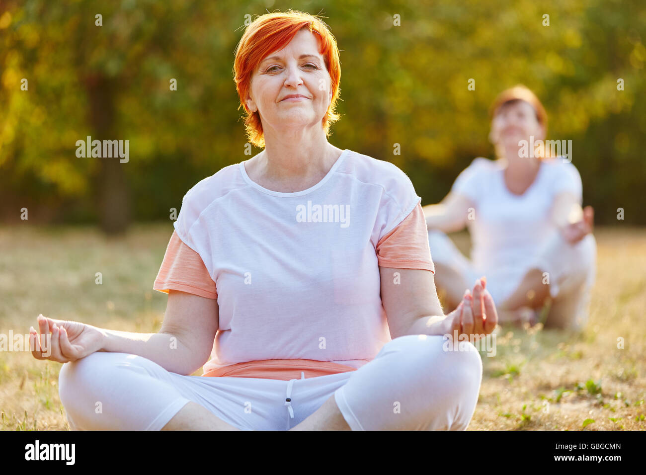 Ältere Frau macht eine Yoga Übung im Sommer in der Natur Stockfoto