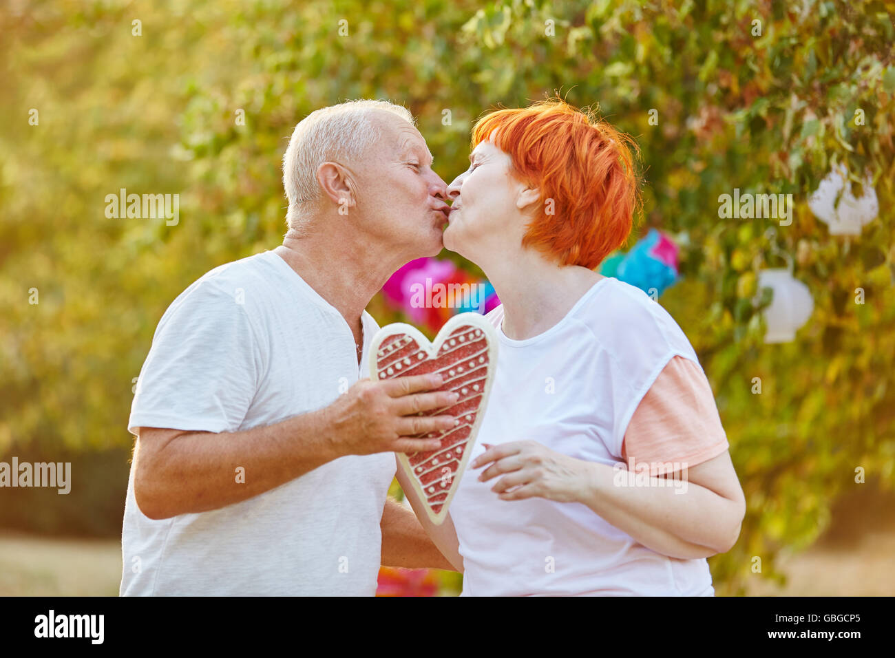 Älteres Paar verliebt küssen und hält ein Herz Stockfoto