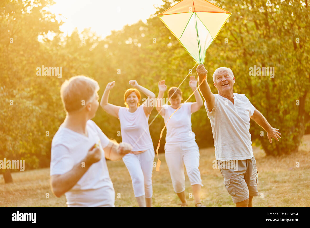 Senioren, lacht und läuft während des Fluges eines Drachens Stockfoto