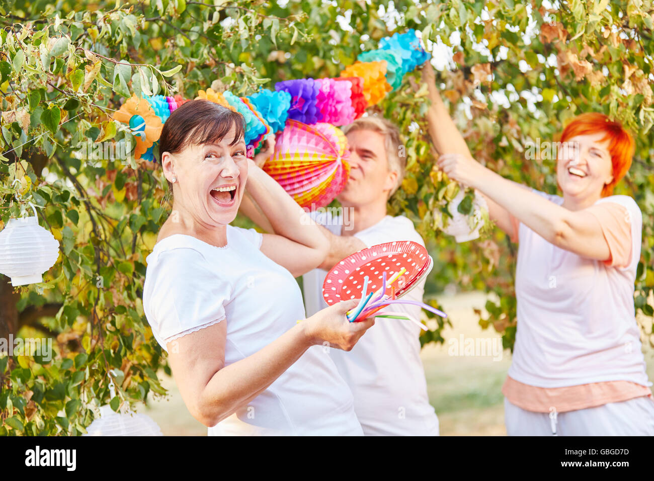 Senioren, die Spaß beim Dekorieren für eine Party in einem Garten Stockfoto