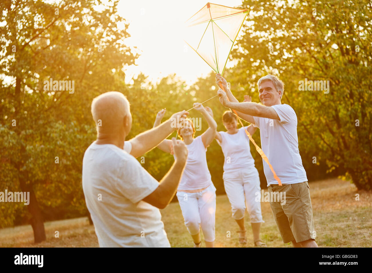 Senioren Freunde Drachensteigen als Team mit Freude im Park im Herbst Stockfoto