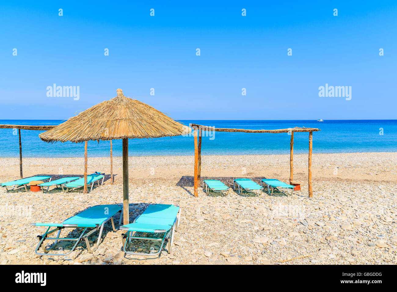 Liegestühle mit Sonnenschirmen am Strand von Potami, Insel Samos, Griechenland Stockfoto