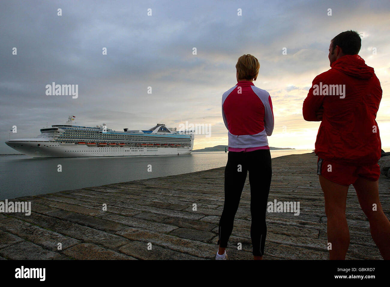 Der Passagierdampfer, die Sea Princess, passiert frühmorgendliche Jogger im Hafen von Dublin kurz vor dem Andocken. Stockfoto