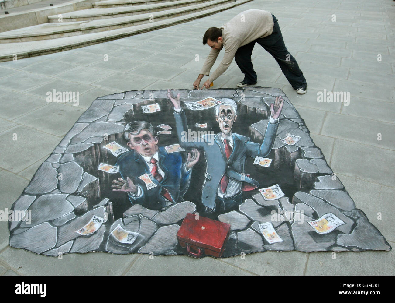 Ein Mann positioniert ein Kunstwerk der Konservativen Partei, das „Labours 1 Billion Black Hole“ zeigt, das auf dem Bürgersteig vor dem Finanzministerium in Westminster, London, platziert ist. Stockfoto