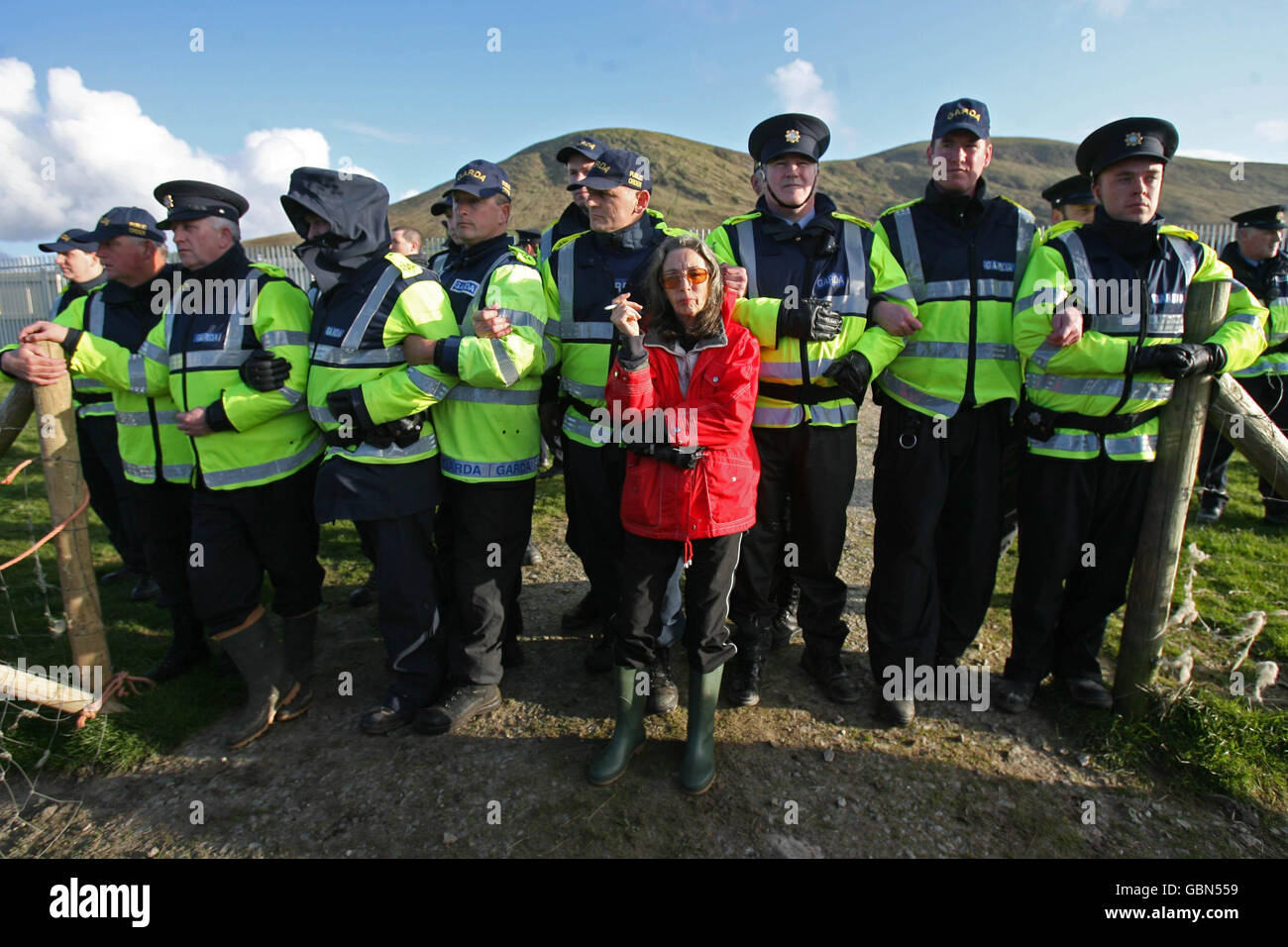 Die Shell to Sea-Aktivistin Maura Harrington lehnt sich an Gardai im Shell-Werk am Strand von Glengad in Co Mayo, Irland. Stockfoto