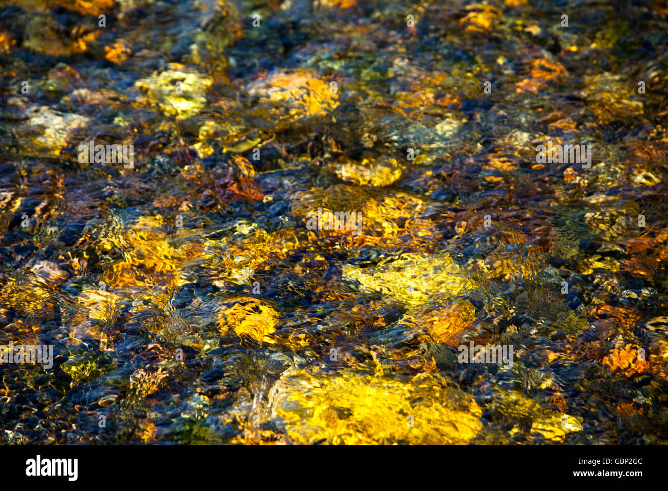 Sonne reflektiert Licht aus steinigen Boden des Flusses. Goldenen Ton Fluss Wasser Textur Hintergrund Stockfoto