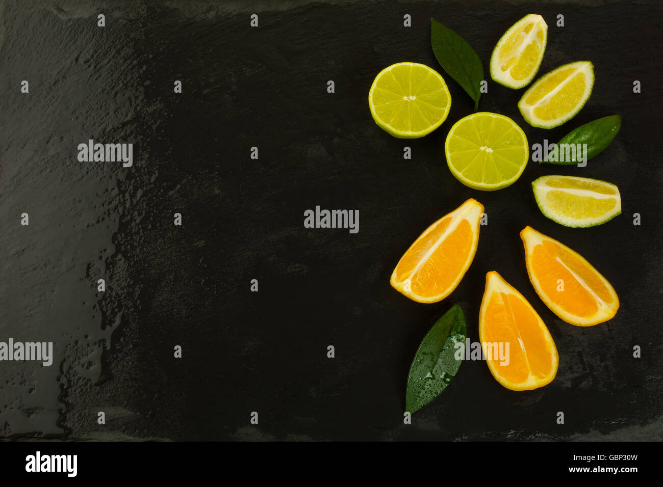 Limette und Zitrone Scheiben auf schwarzem Hintergrund. Gesunde Ernährung-Konzept mit reifen Früchten gemischt. Vegane und vegetarische Lebensmittel wie Obst Stockfoto