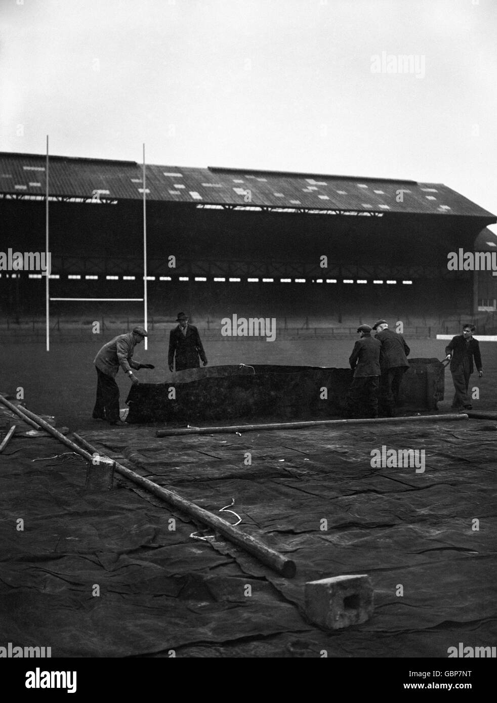 Vorsichtsmaßnahmen, die auf dem Twickenham Rugby-Gelände gegen möglichen Frost getroffen werden, der den Boden beeinträchtigt. Arbeiter legen den Spielplatz mit Plane, um ihn zu schützen. Stockfoto