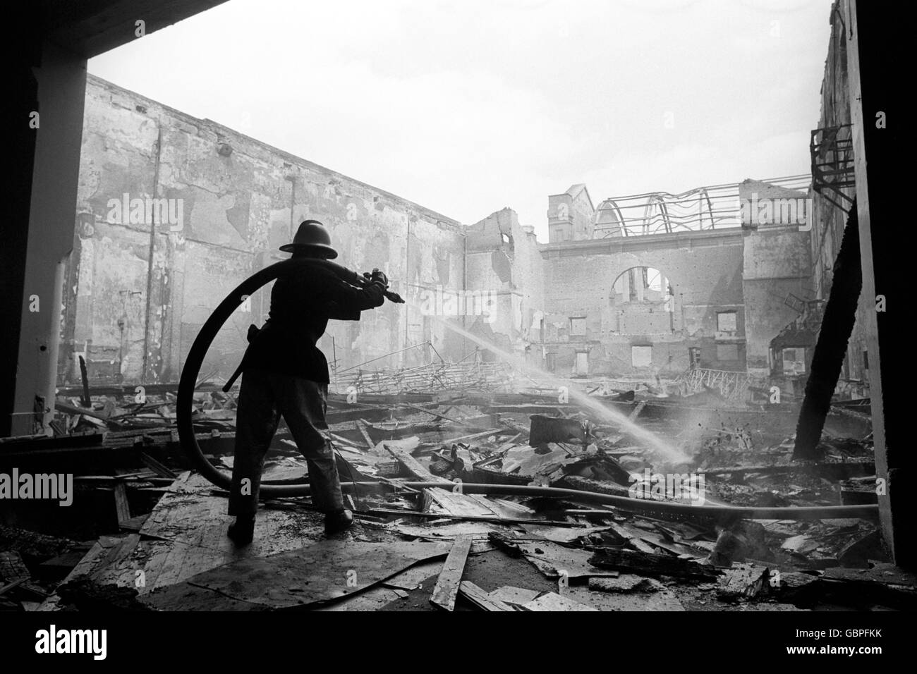 Die Feuerwehrleute, die nach einem Brand noch immer die Dämmung ausgemerzt haben, haben die große Halle des Alexandra Palace im Norden Londons vollständig entkuttet. Stockfoto