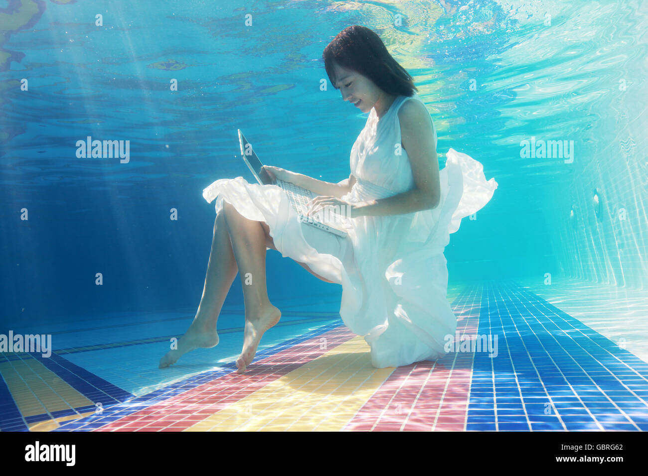 Junge Frauen nutzen Computer unter Wasser Stockfoto