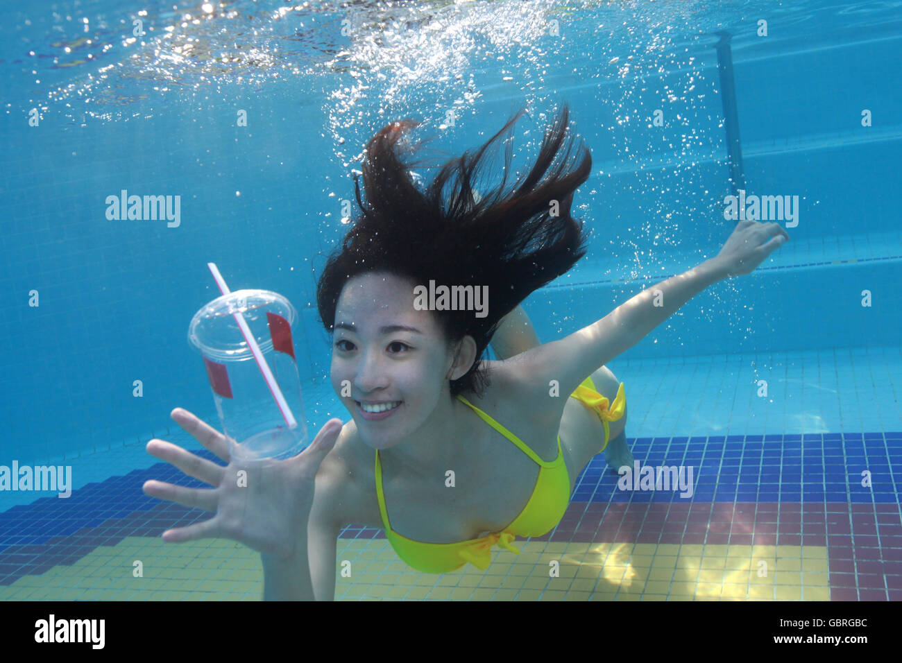 Junge Frau, die im Wasser schwimmen Stockfoto