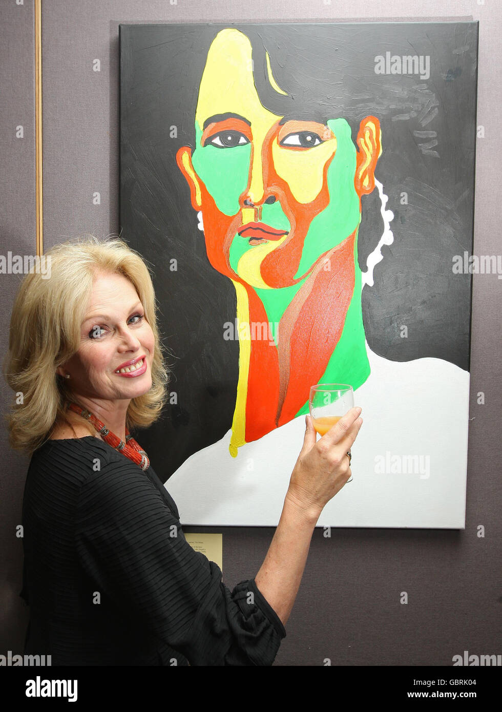 Joanna Lumley steht vor einem Porträt der birmanischen Oppositionsführerin Aung San Suu Kyi des burmesischen Künstlers Htein Lin bei einer Veranstaltung zur Feier des 64. Geburtstages von Suu Kyi am 19. Juni und der 20. Jubiläumsfeier von Project Burma im Bloomsbury Auction House, Mayfair, London. Stockfoto