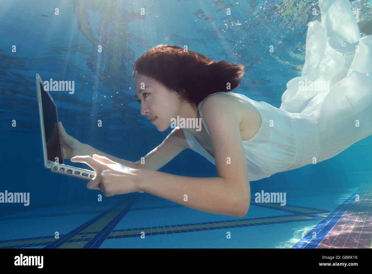 Junge Frauen nutzen Computer unter Wasser Stockfoto
