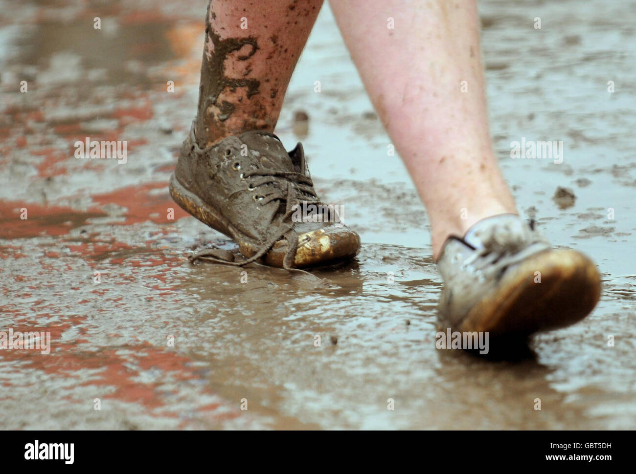 Glastonbury Festival 2009 - Erster Tag. Ein Mann geht während des Glastonbury Festivals 2009 in Pilton, Somerset, durch Schlamm. Stockfoto