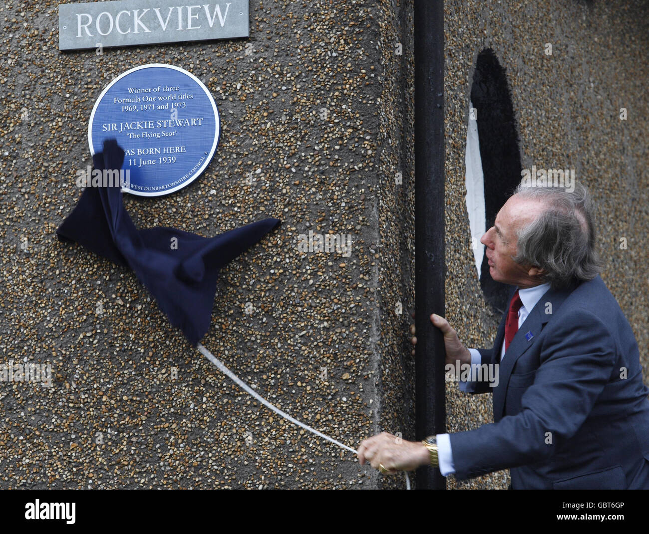 Jackie Stewart machte einen Freeman aus West Dunbartonshire. Sir Jackie Stewart wird als Freeman aus West Dunbartonshire geehrt, als er eine Gedenktafel an dem Haus enthüllt, in dem er in Dumbarton aufgewachsen ist. Stockfoto